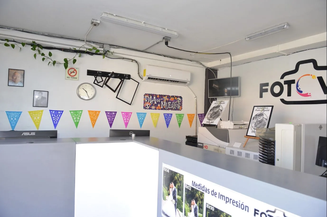 Mostrador y área de impresión del laboratorio, con papel picado de Día de Muertos