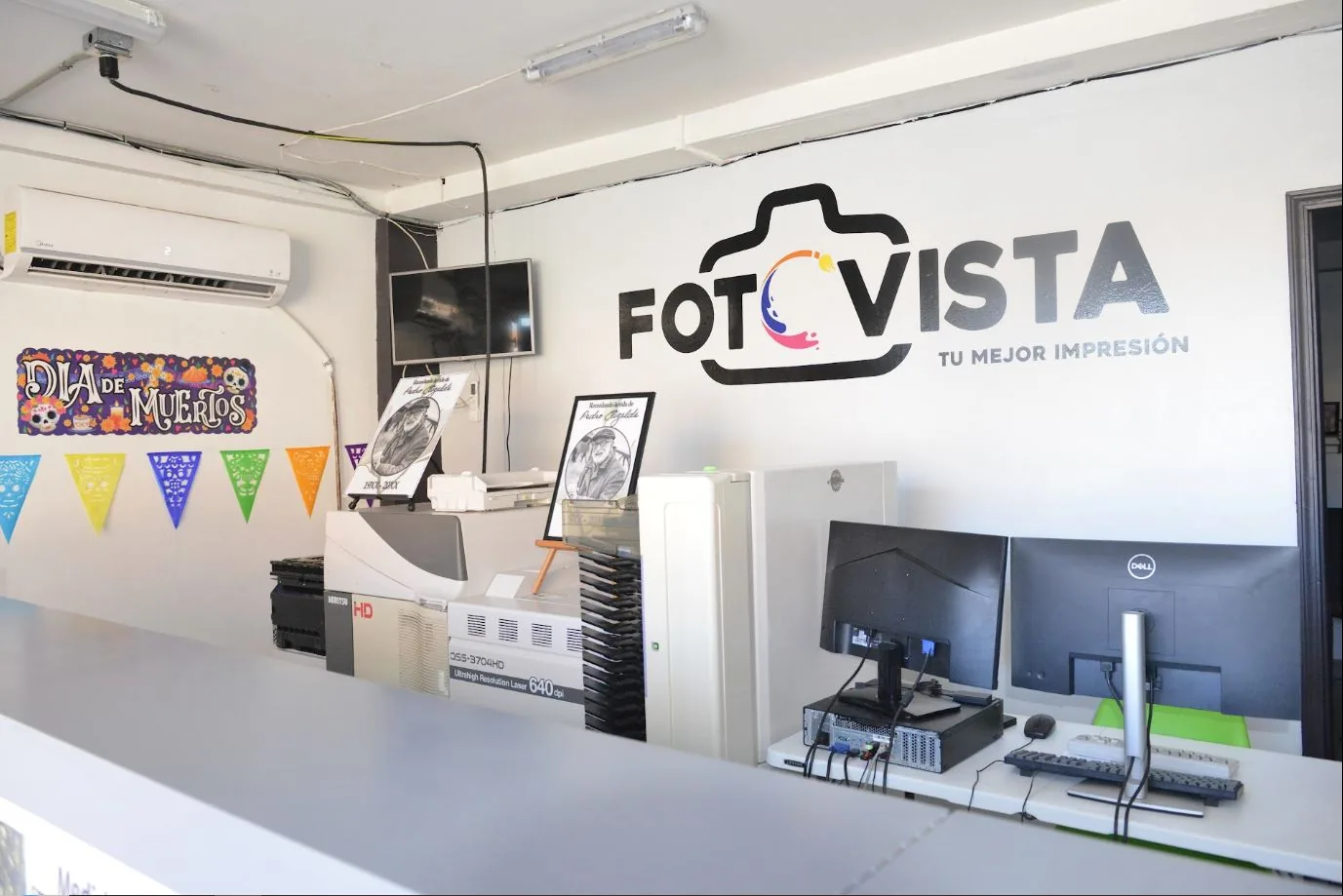Logotipo de Fotovista en la pared del laboratorio, junto a las impresoras